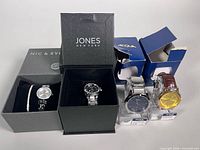 Overall view of four boxed watches and bracelet showing brands and packaging
