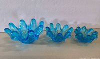 Front view of three blue glass ruffled bowls in graduated sizes