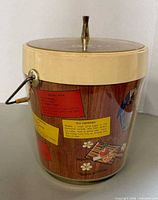 Side view of ice bucket showing woodgrain print, cocktail graphics, handle and lid