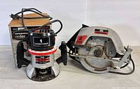 Router with original box alongside circular saw front view