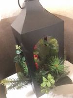 Black metal lantern with greenery and berries