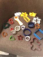 Group of assorted plastic and metal cookie cutters with tea strainer on chair