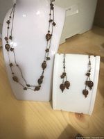 Brown multi-strand bead necklace on display bust with matching earrings on stand