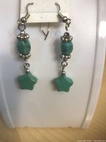 Front view of faux turquoise bead earrings with green star charms