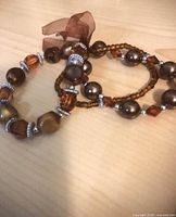 Brown and silver-tone acrylic stretch bracelets with ribbon tie