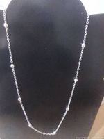 Silver-tone chain with spaced beads displayed on bust