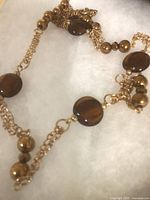 Brown and gold 32 in necklace showing round tiger-eye style beads and gold-plated chain links