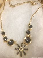 Gold-plated necklace with dark grey stones and starburst pendant