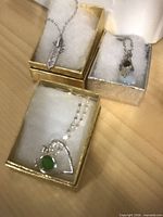 Overview of three boxed silver-tone pendant necklaces