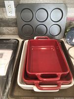 Stacked Bobby Flay red pans, Good Cook white pan, muffin-top pan and cookie sheets