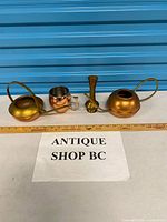 All four metal pieces side by side with ruler for scale