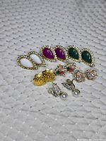 All seven pairs of earrings arranged on fabric background