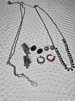 Full lot view showing two necklaces and four earring pairs laid on fabric