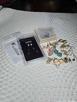 Group shot showing packaged Pierced Nation Illusion set, loose stud earrings, small box