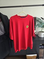 Front view of red Ferrari T-shirt on hanger showing overall appearance and chest logo