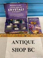 Closed and open view of display box, compartments with stones, booklet visible, ruler for scale