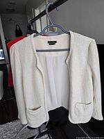 Full front view of ivory cropped jacket on hanger