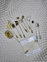 All eleven stick pins laid out showing decorative tops and shafts, Triad Canada card visible