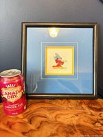 Full view of framed print beside soda can for scale