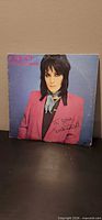 Front album cover portrait of Joan Jett in pink blazer with printed ‘I Love Rock n Roll’ text