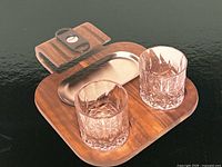 Marketing image showing walnut board, two glasses, ashtray and cutter