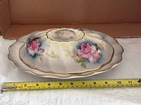 Top view of covered dish showing floral design and tape measure for length