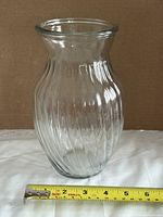 full view front of clear spiral ribbed glass vase with tape for scale
