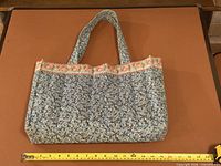 Front view of quilted floral handbag with tape for width measurement