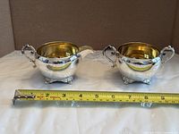 Front view of creamer and sugar bowl with tape for width reference