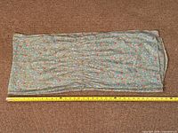 Full view of scarf laid flat beside tape measure