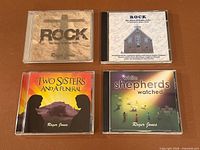 All four Roger Jones CDs laid out: ROCK tan cover, ROCK church cover, Two Sisters and a Funeral, While Shepherds Watched