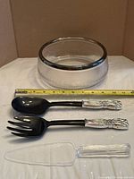 bowl with three utensils and measuring tape showing diameter