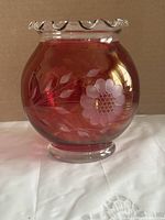 Front view of cranberry glass vase showing etched flower and leaves