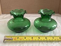 Front view of both green ruffled glass vases beside ruler showing width about 5 inches