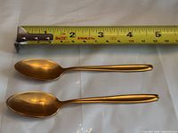 Two gold plated Insilco teaspoons beside tape measure showing 6 in length
