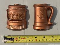 Front view of both brass tone wall plaques beside ruler