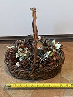 Top view of wicker basket showing pinecones, birds, greenery and light string