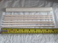 Six plastic chopsticks laid beside a tape measure showing roughly 10.5 inch length and paper sleeve