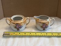 front view of both porcelain lustreware pieces with tape for width reference