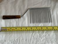 Full view of cake cutter next to tape measure showing length