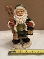 Front view showing Santa holding skis and lantern with measuring tape for scale