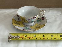 Teacup on saucer with measuring tape showing approximate length