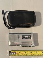 Recorder and pouch on table with tape measure showing size