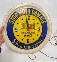 Front view of Berlou advertising clock showing dial graphics and hands