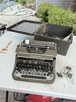 Typewriter with case base and lid in background