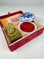 Open brocade box showing snake seal, ink pot with lid removed, red ink visible