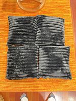 Four square dark grey ribbed pillows laid out