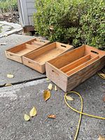 Three wooden crates side by side on pavement