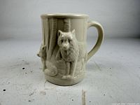 Front view of porcelain mug showing primary wolf relief and handle