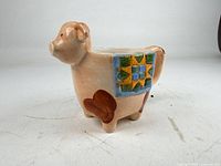 Left side view of pig-shaped mug showing quilt motif and legs